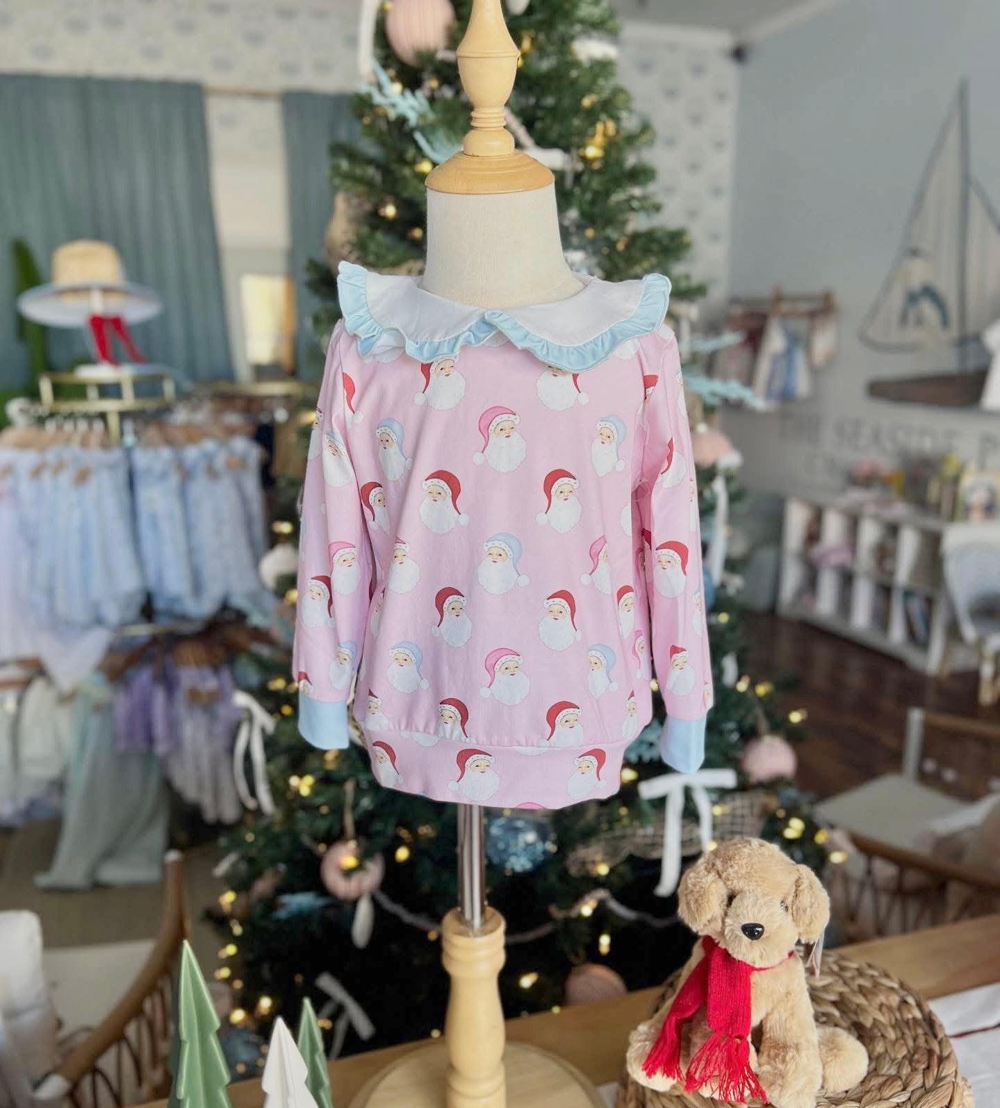 Children's pink sweater with unicorn pattern on a mannequin in a store setting.